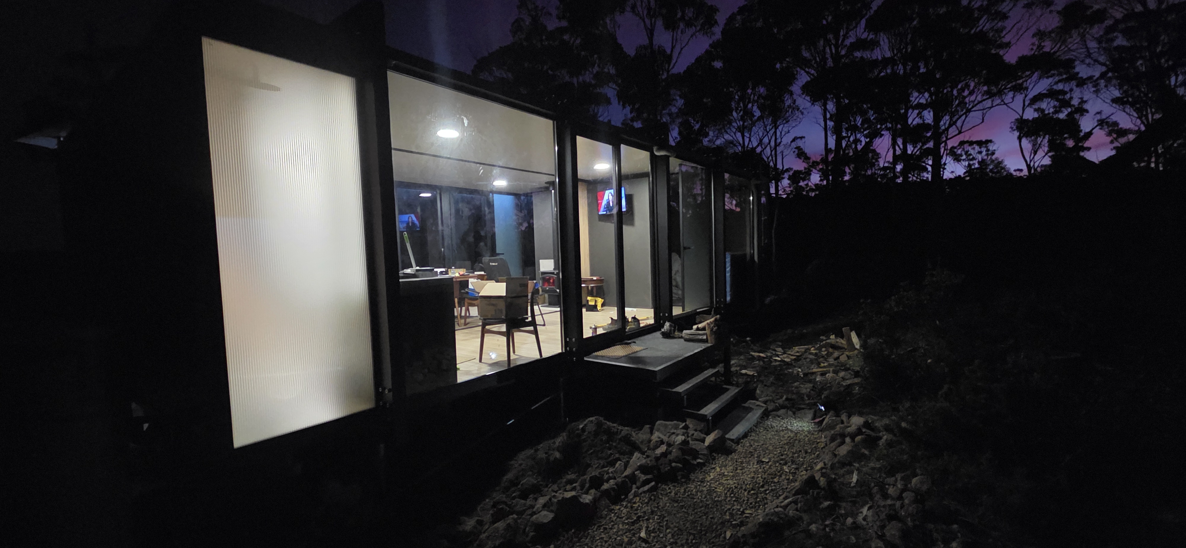 Glass entrance and warmly lit interior of the pod at dusk